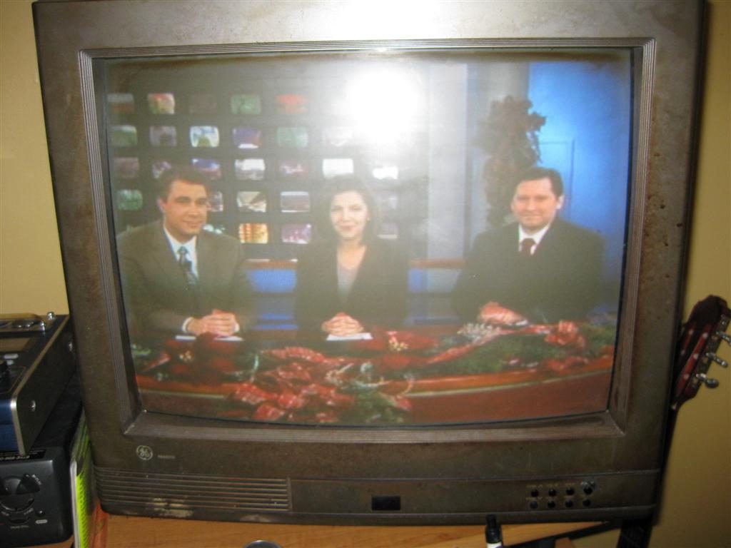 television with image of newscasters surrounded by Christmas decorations